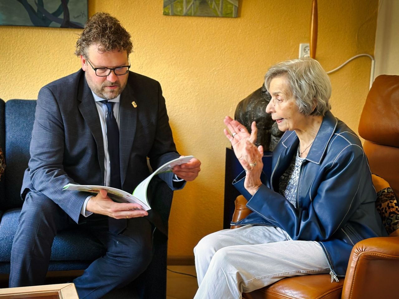 Eugènie overhandigt het eerste exemplaar aan burgemeester Maarten Poorter, die erin bladert